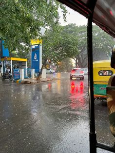 cars are driving down the road in the rain, with gas pumps on either side