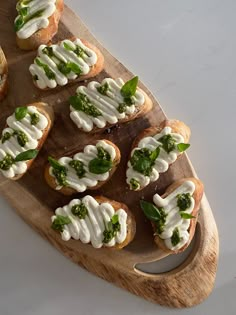 small appetizers are arranged on a wooden platter with green garnishes