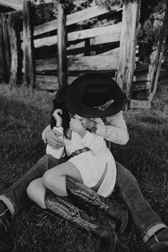 black and white photograph of a boy sitting on the ground with a cowboy hat over his head