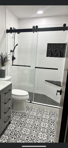 a bathroom with black and white tile flooring next to a walk in shower stall