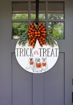 a trick or treat sign hanging on the front door with pumpkins and dog faces