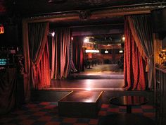 an empty stage with red curtains and checkered floor