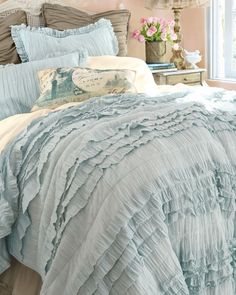 a bed with blue and white comforters in a bedroom next to a window filled with pink flowers