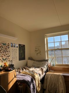 an unmade bed sitting in a bedroom next to a window