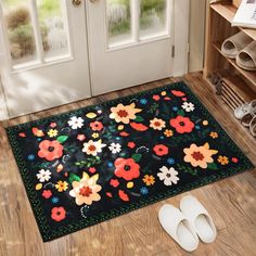 a pair of slippers sitting on the floor next to a door mat with flowers