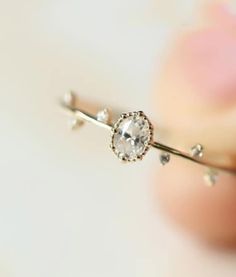 a close up of a person's hand holding a ring with a diamond on it