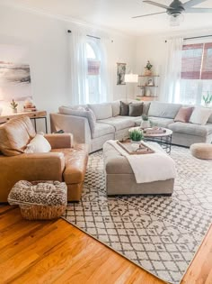 a living room filled with furniture and a large rug on top of a hard wood floor