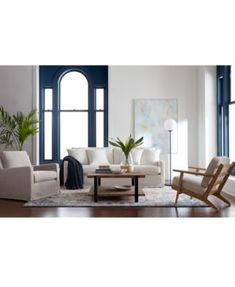 a living room filled with white furniture and large windows next to a wooden coffee table