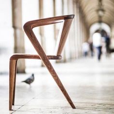 a wooden chair sitting on top of a tiled floor next to a bird perched on the ground