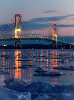 a bridge that is over some ice in the water with lights shining on it's sides