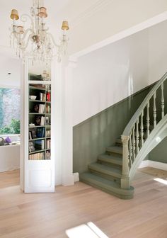 a room with a book shelf, chandelier and stairs