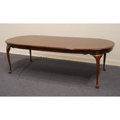 a wooden table sitting on top of a carpeted floor next to a white wall