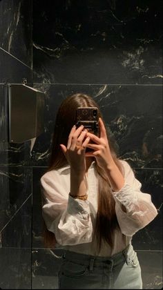 a woman taking a selfie in front of a mirror with her hair pulled back