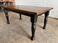 a wooden table with two black legs in a garage