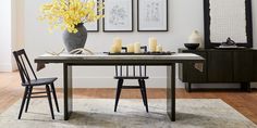 a dining room table with chairs and a vase filled with yellow flowers on top of it