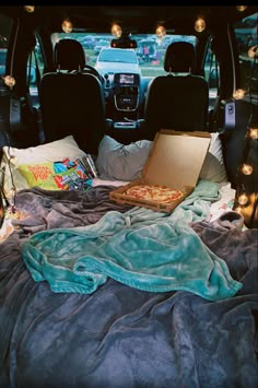 the back of a van with pizza and blankets on it's bed in the trunk