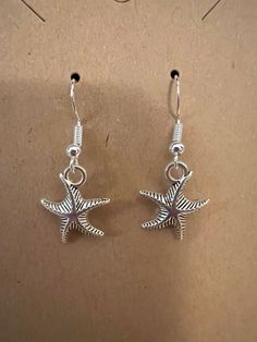 Small starfish on silver nickel free hypoallergenic fishhook earrings Summer Starfish Charm Drop Earrings, Sterling Silver Starfish Charm Dangle Earrings, Silver Drop Earrings With Starfish Charm, Silver Star Earrings For Summer, Summer Starfish Charm Dangle Earrings, Nickel-free Starfish Earrings As Gift, Nickel-free Starfish Earrings For Gifts, Starfish-shaped Nickel-free Earrings For Gifts, Starfish Nickel-free Earrings For Gift