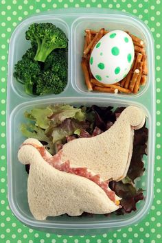 a plastic container filled with food on top of a green and white polka dot tablecloth