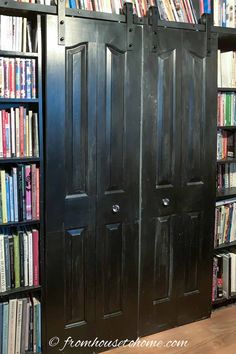 two black doors are open in front of a bookshelf with many books on it