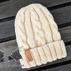 a white knitted hat sitting on top of a wooden bench