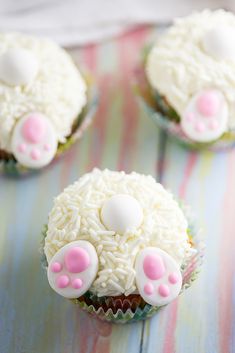 some cupcakes with white frosting and pink paws on top are sitting on a table