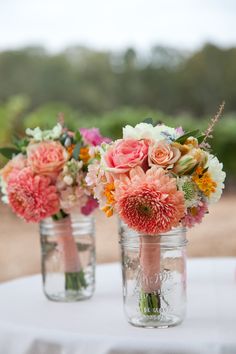 there are many vases that have flowers in them on the table with pink and white flowers