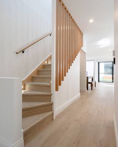 a white staircase with wooden handrails in a house