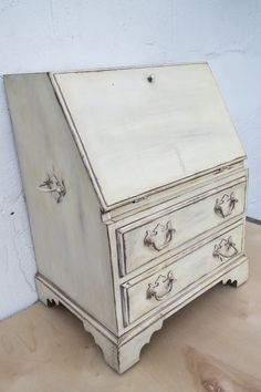 an old white dresser sitting on top of a wooden table