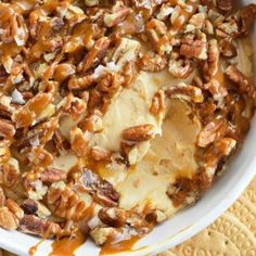 a bowl filled with nuts and cheese on top of a wooden table next to a napkin