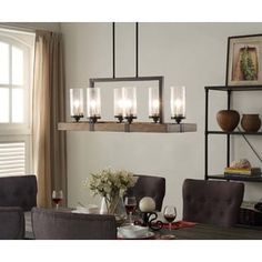 a chandelier hanging over a dining room table with chairs and vases on it