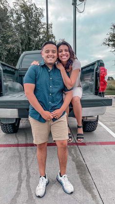 a man and woman standing in front of a pick up truck with their arms around each other