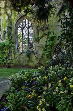 an old building with lots of plants and flowers in the foreground, next to a stone walkway