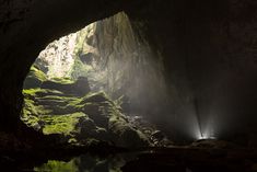 the light at the end of the tunnel shines brightly in the dark, with green moss growing on the rocks