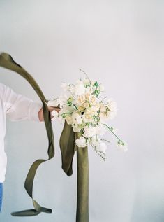 a man is holding a bouquet of flowers in front of his face with a green ribbon around it