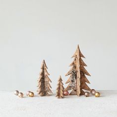 three small wooden christmas trees with ornaments on the bottom and one standing out from the others