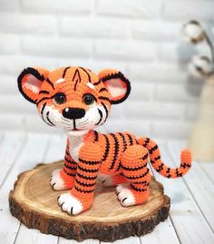 a crocheted tiger figurine sitting on top of a piece of wood