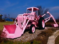 a pink bulldozer sitting on top of a pile of dirt