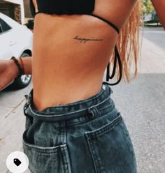 a woman with a small tattoo on her lower back and the word happiness written in cursive writing