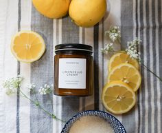 some lemons and oranges on a table with a jar of honey next to them