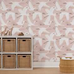 a wallpapered room with baskets and toys on the floor next to an empty dresser