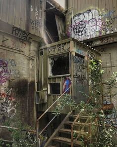 an old run down building with graffiti on the walls and stairs leading up to it