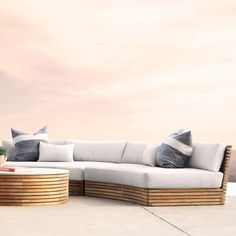 a couch with pillows on it sitting in front of a wooden table and planter