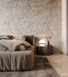 a large bed sitting next to a lamp on top of a wooden table in front of a stone wall