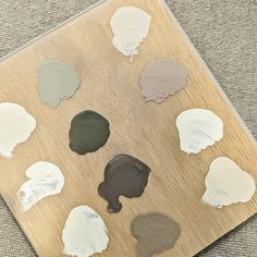 several different shades of paint sitting on top of a wooden board next to a gray carpet