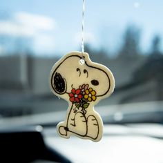 a wooden ornament with a snoopy holding flowers in it's mouth