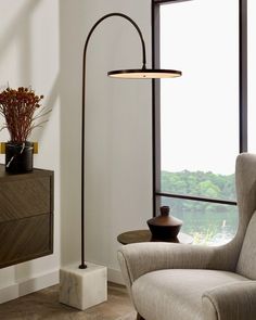 a living room with a chair, lamp and large window overlooking the water in the distance