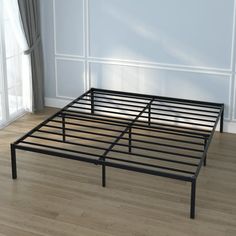 a metal bed frame sitting on top of a hard wood floor next to a window