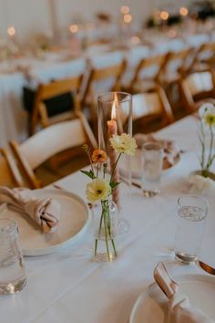 the table is set with white linens, silverware and flowers in vases