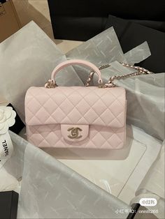 a pink chanel bag sitting on top of a table next to some other items