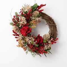 a wreath with red flowers and greenery hanging on a wall